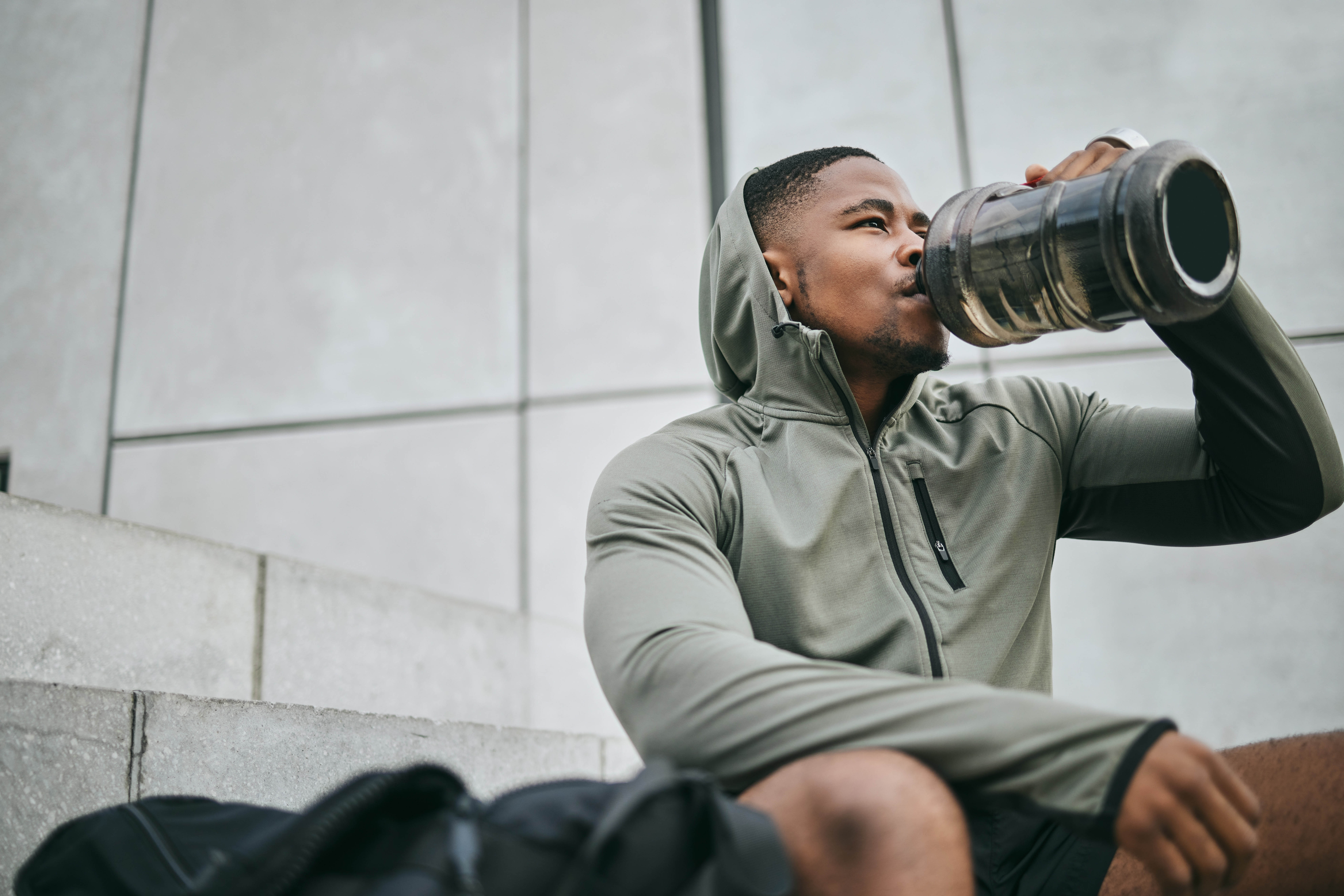Man drinking his water as he recovers from a workout Man drinking his water as he recovers from a workout